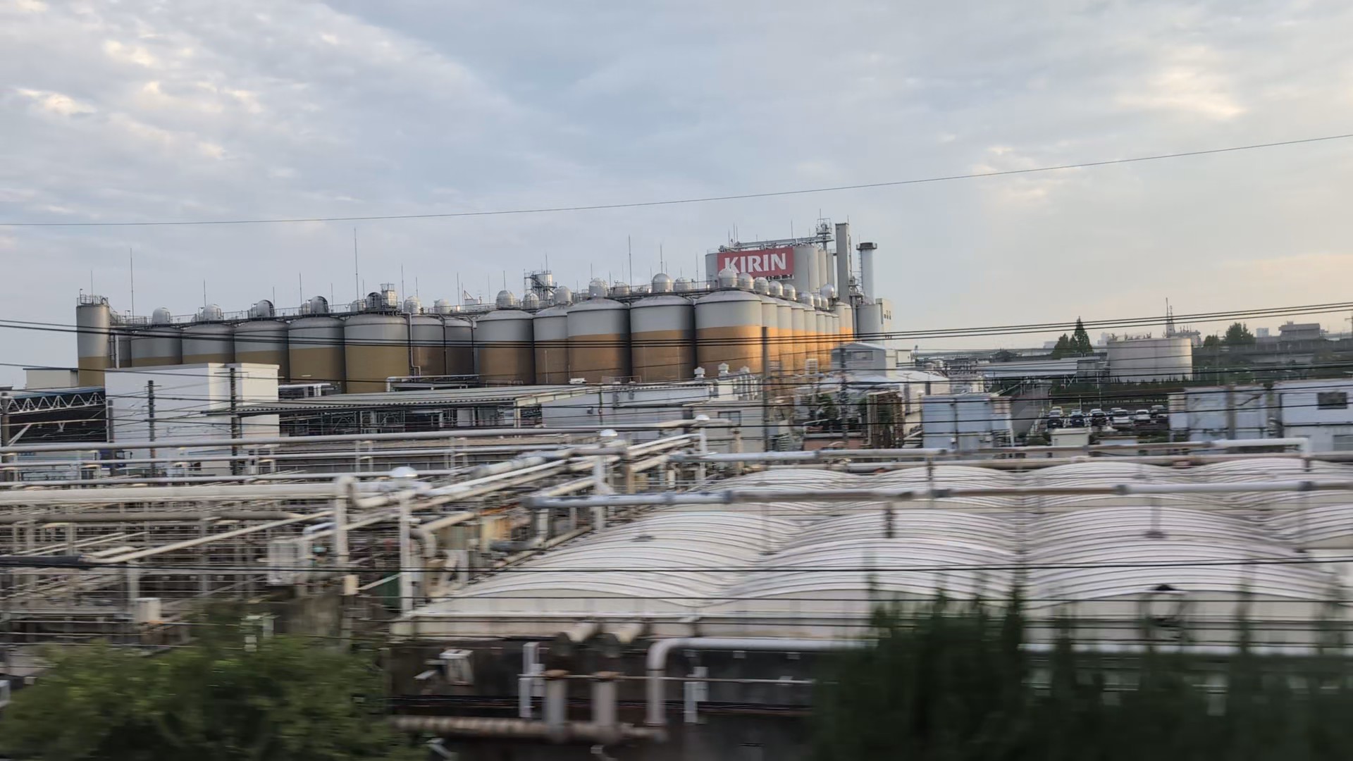 A row of gold-and-silver tanks and the KIRIN name at the Nagoya brewery, seen from the Shinkansen.