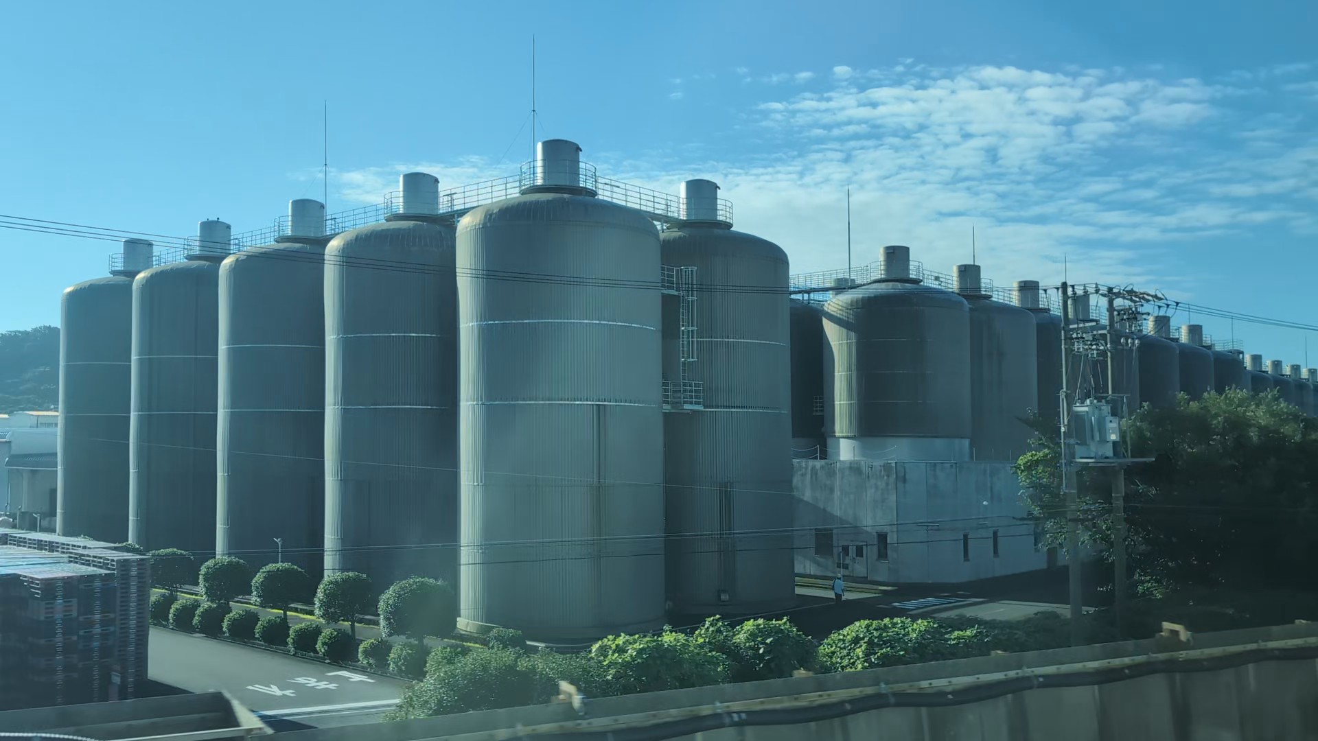 Tall silver tanks at Sapporo Beer’s Shizuoka brewery in Yaizu, photographed through the Shinkansen window.