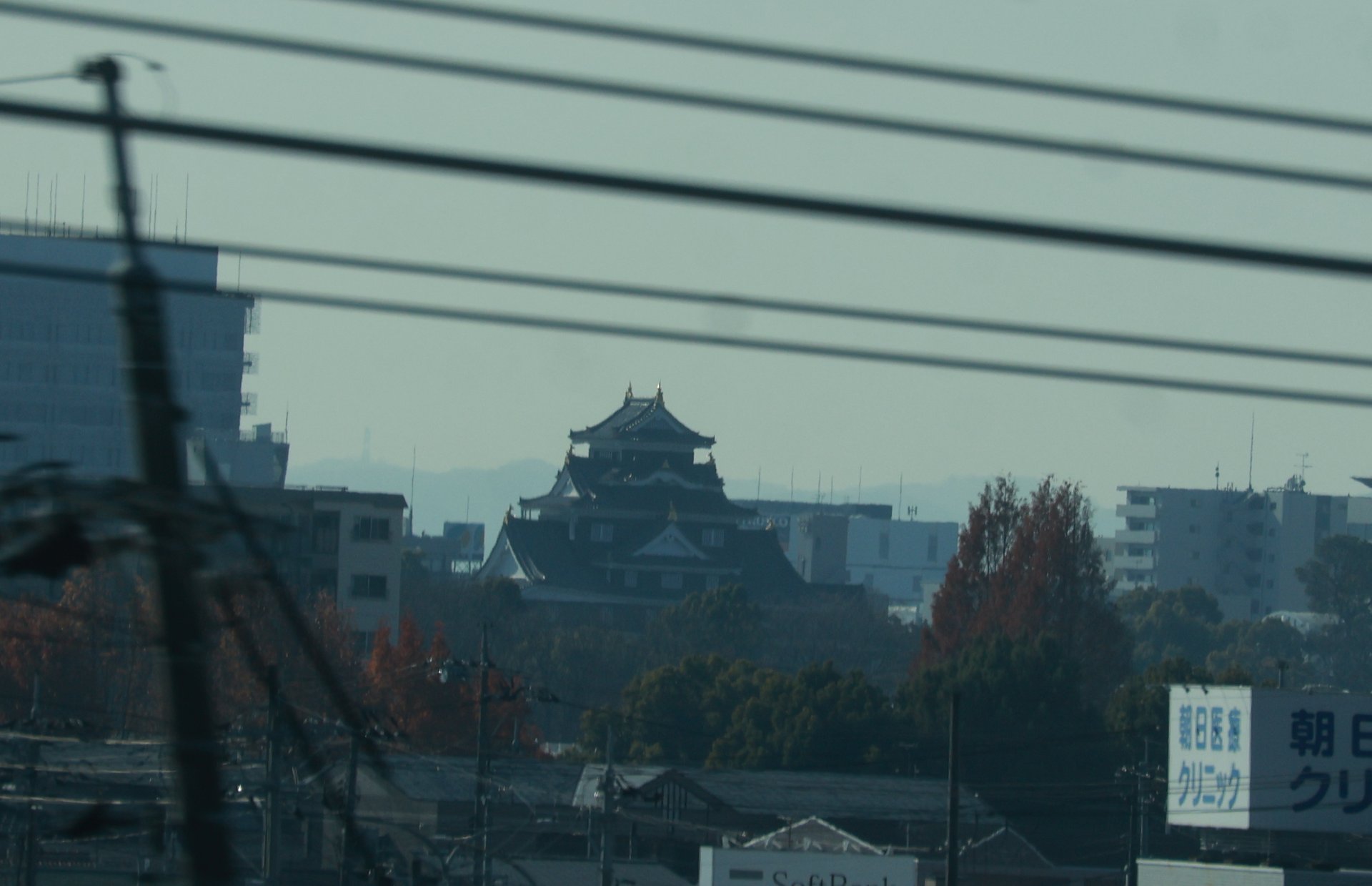 Okayama Castle between city buildings and the hills beyond