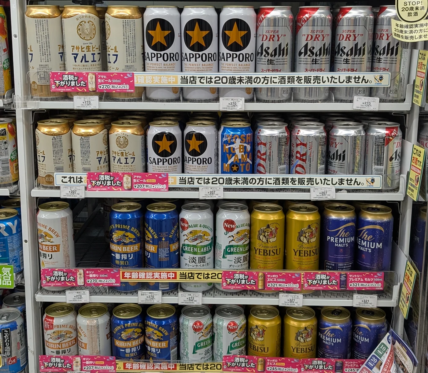 A refrigerated shop shelf displaying Asahi, Sapporo, Kirin, Suntory and other Japanese beer and beer-style drinks.