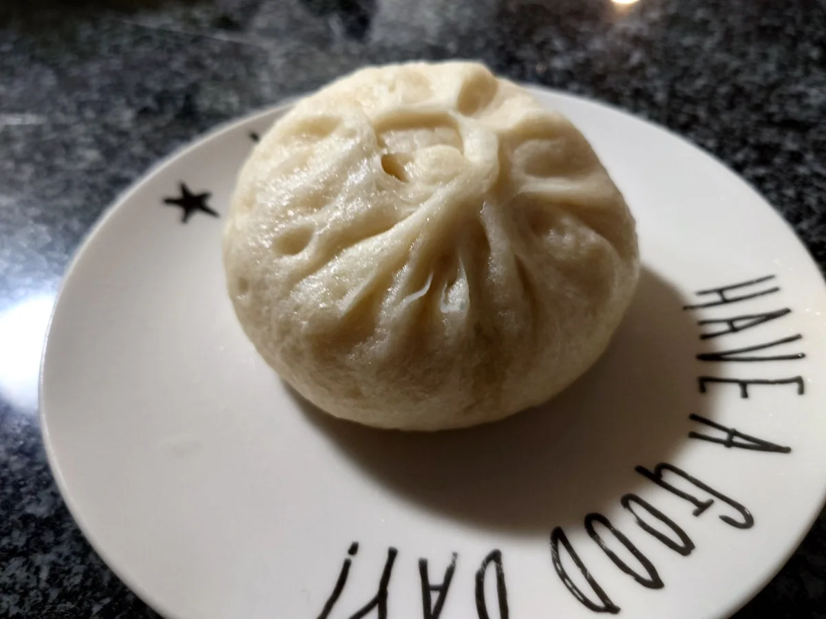 A white steamed bun with a savoury pork filling