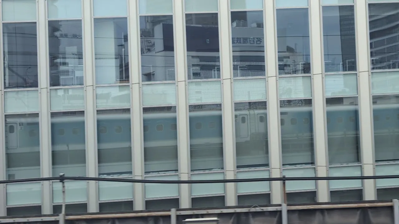 Just before Nagoya, the Shinkansen reflected in a building with tall windows