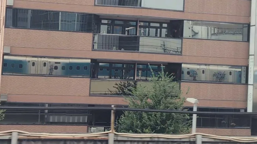 Just after leaving Nagoya, the Shinkansen reflected in the glass of a trackside building