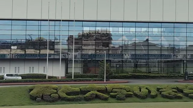 Close-up of the blue train reflected along the bottom of the POLA factory glass