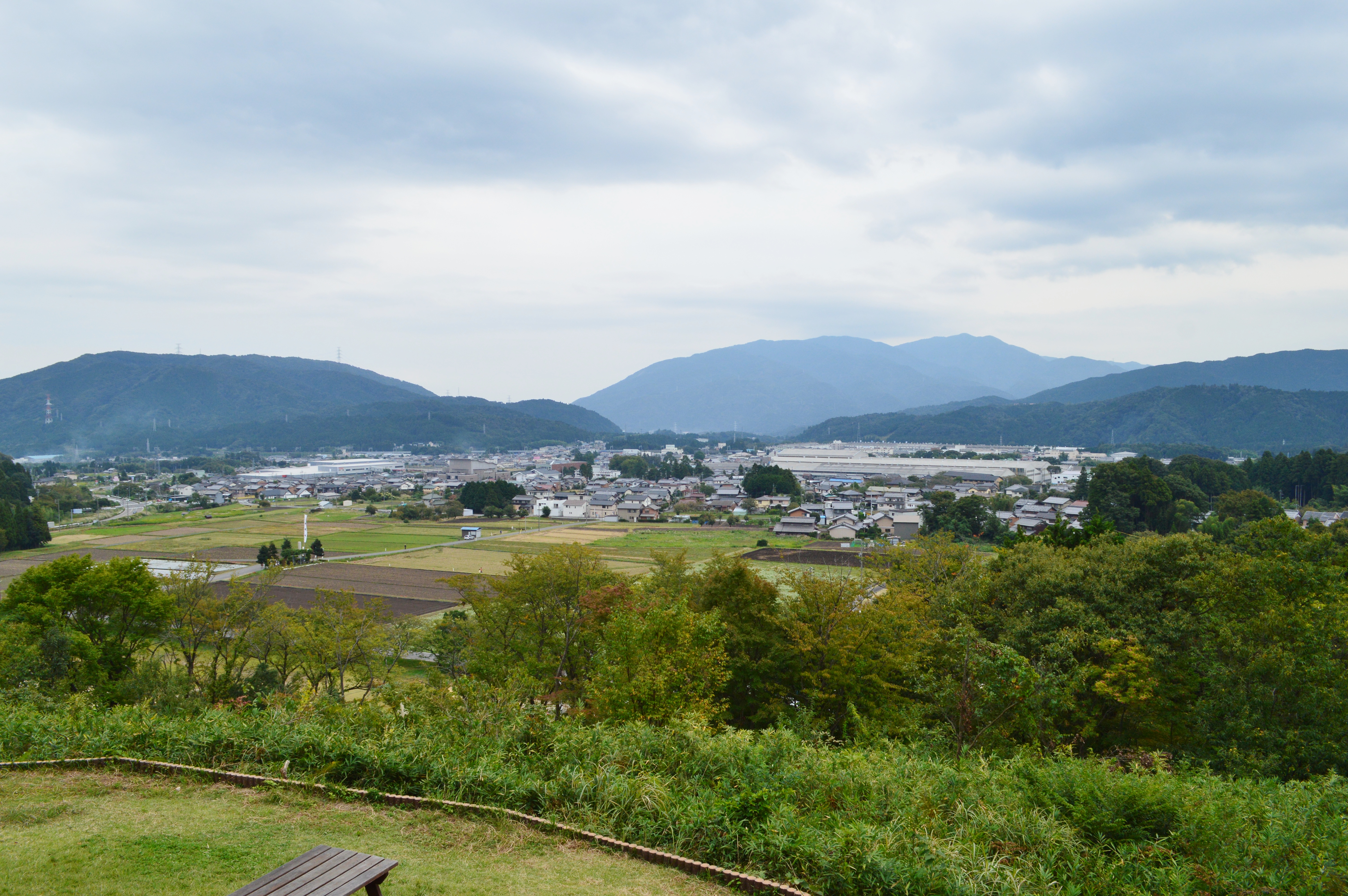 石田三成陣跡から見渡す関ケ原の町。田畑や建物の向こうを山々が囲む。