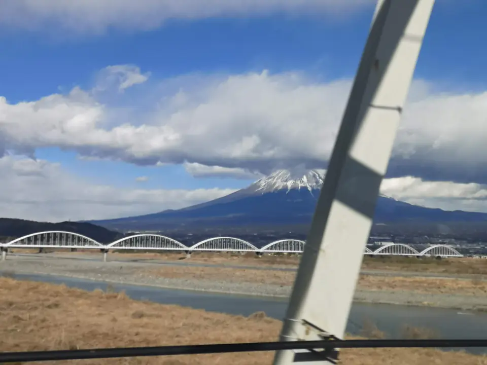 富士川の白いアーチ橋の向こうに立つ冠雪の富士山