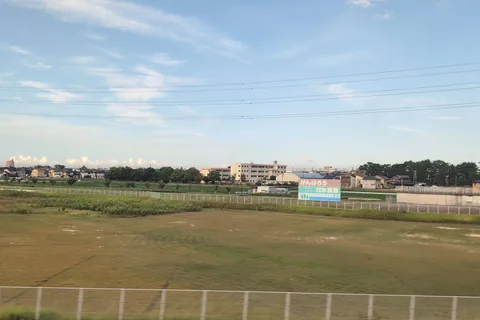 Un cartel rojo, verde y azul más allá de los campos que dice Ganbarō Nihon nōgyō