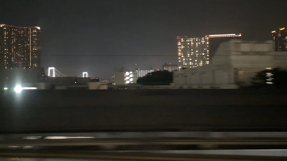Weiß beleuchtete Türme der Rainbow Bridge hinter der Stadt bei Nacht