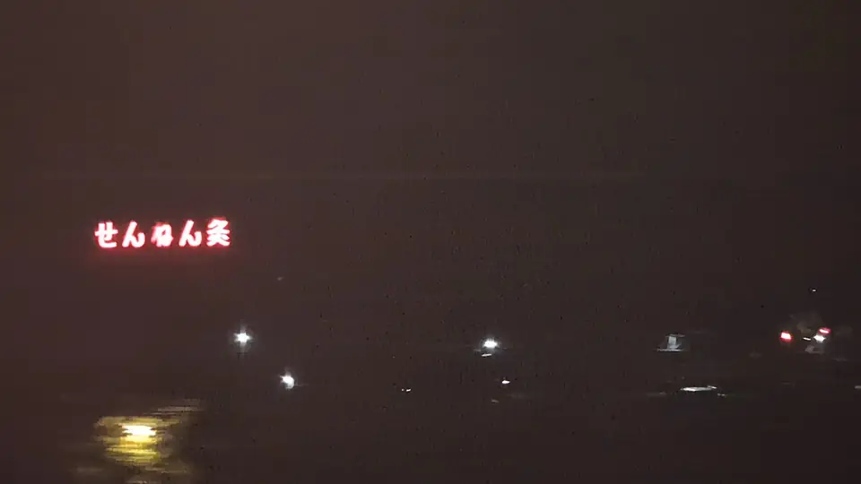 夜の車窓に赤く光るせんねん灸の看板