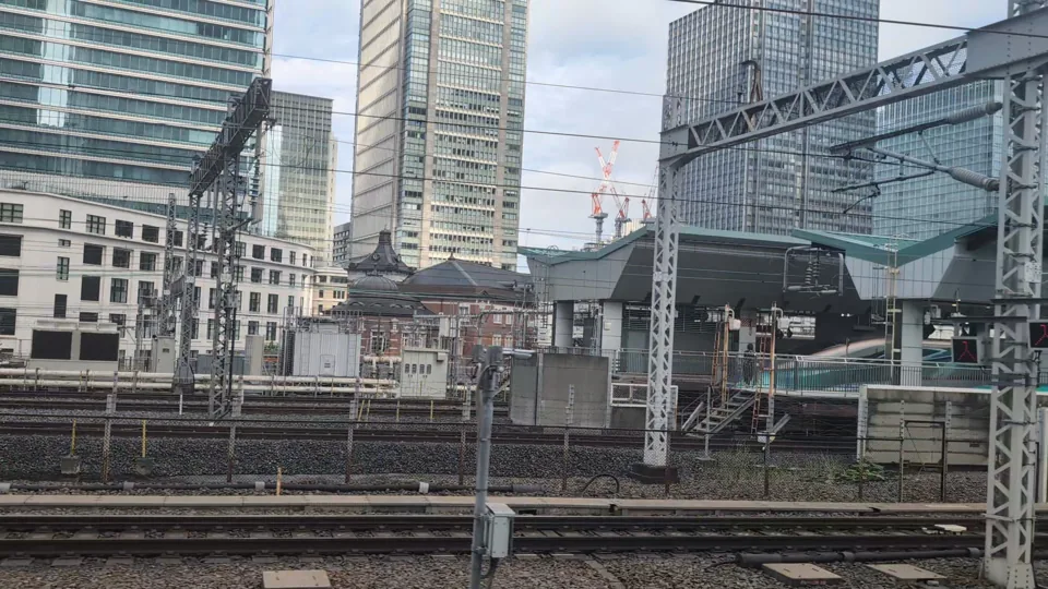 Das Marunouchi-Gebäude des Bahnhofs Tokio und Hochhäuser hinter den Gleisen und Bahnsteigen