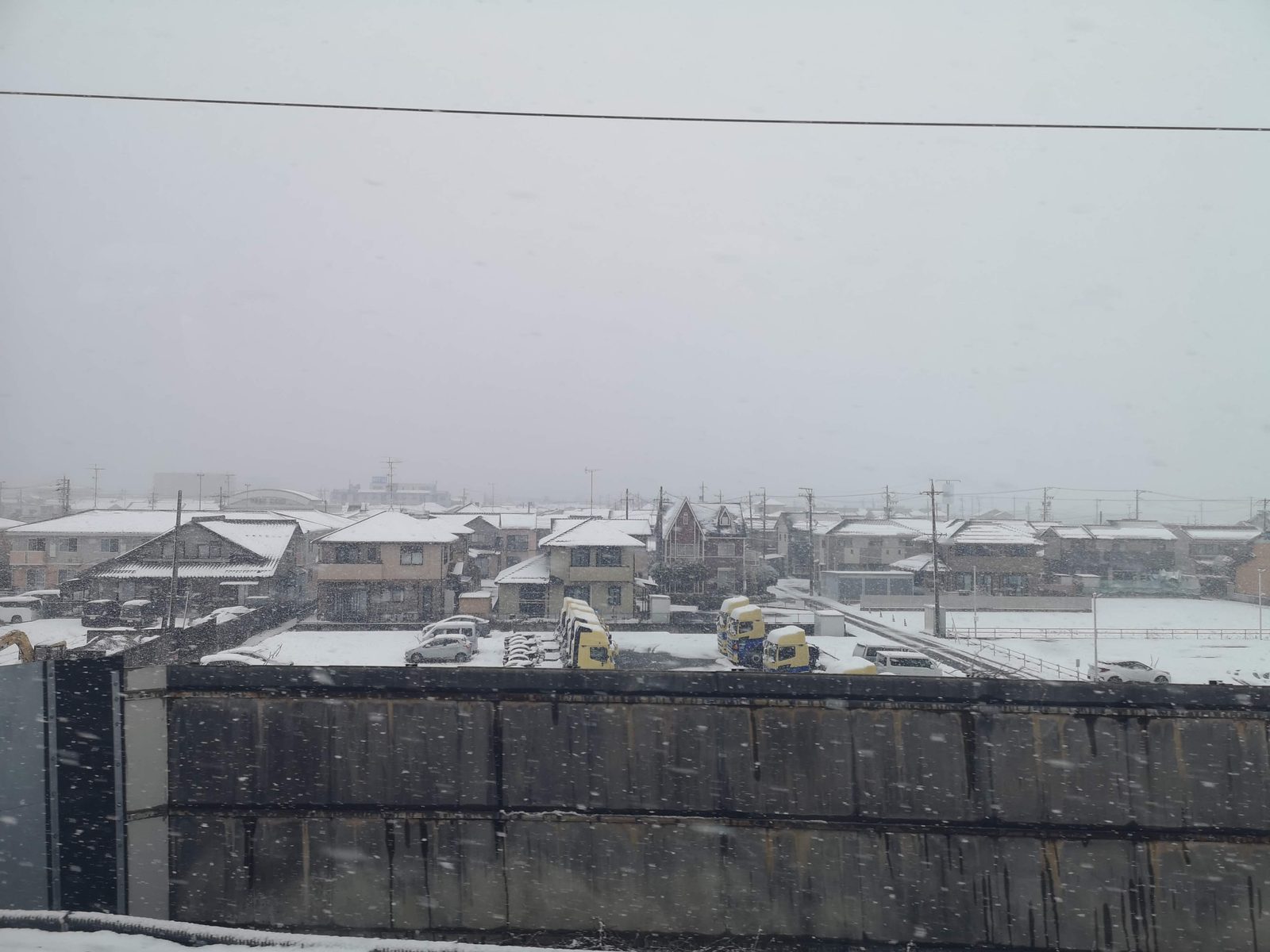 強い雪が降る市街地を東海道新幹線の車窓から見る